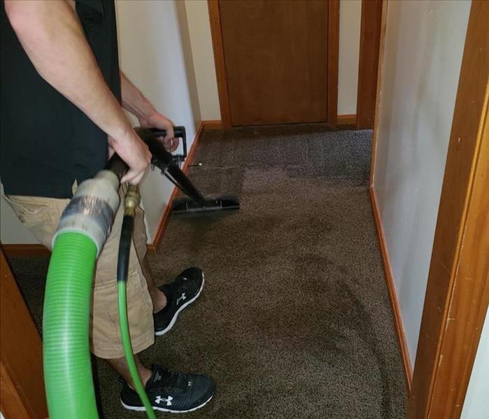 SERVPRO technician is very meticulously cleaning hallway carpet